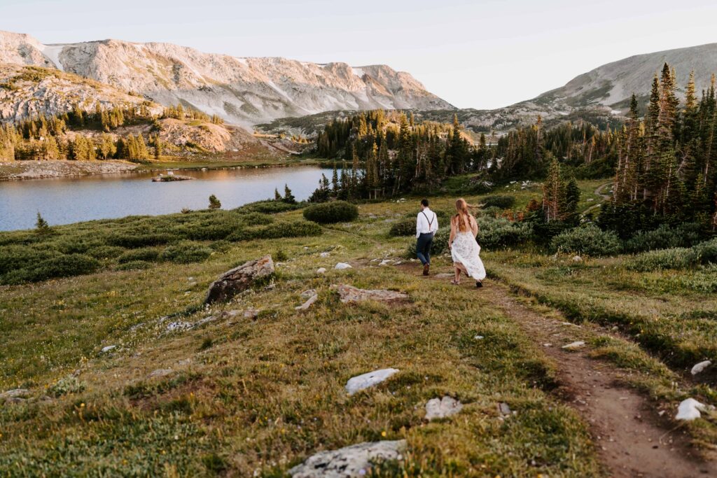 Couple walks to an alpine lake for their sunrise portraits during their camping elopement in Wyoming
