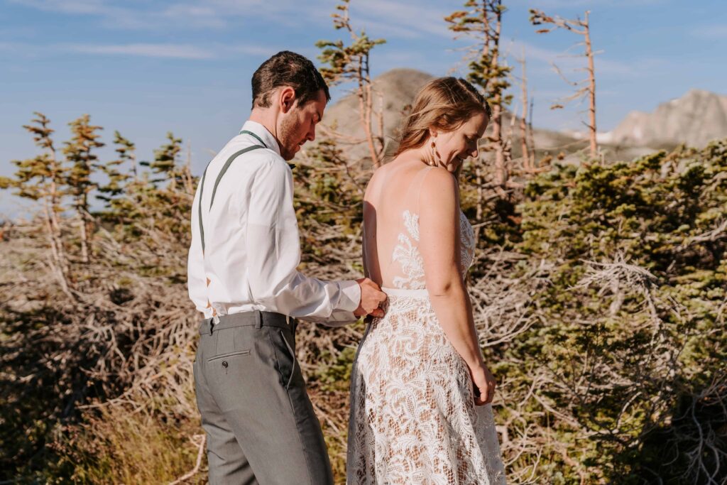 Groom zips up brides dress for their Camping Elopement in Wyoming