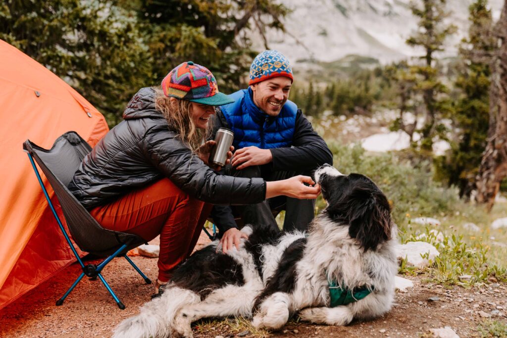 Couple sits at their campsite together with their dog