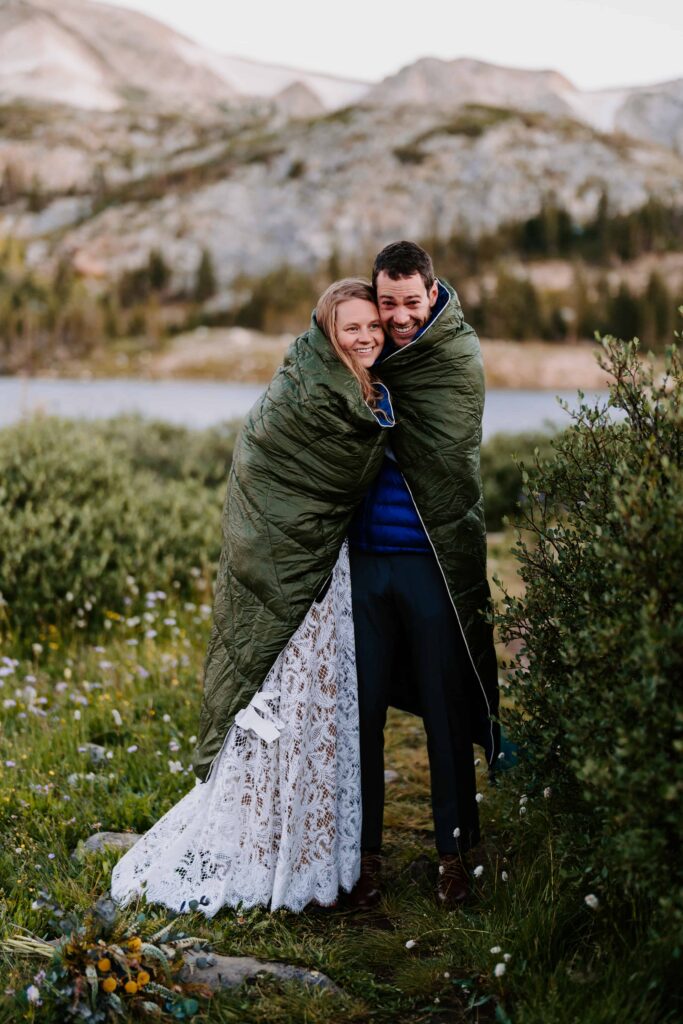 Bride and groom share a sleeping bag to warm up