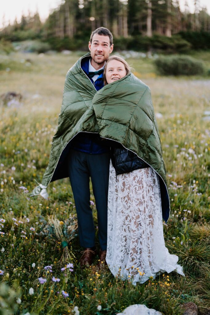 Bride and groom share a sleeping bag to warm up