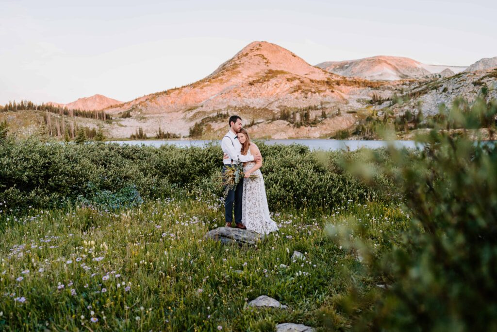 Couple stands in a field of wildflowers for their wedding portraits