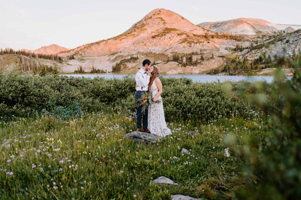Couple stands in a field of wildflowers for their wedding portraits