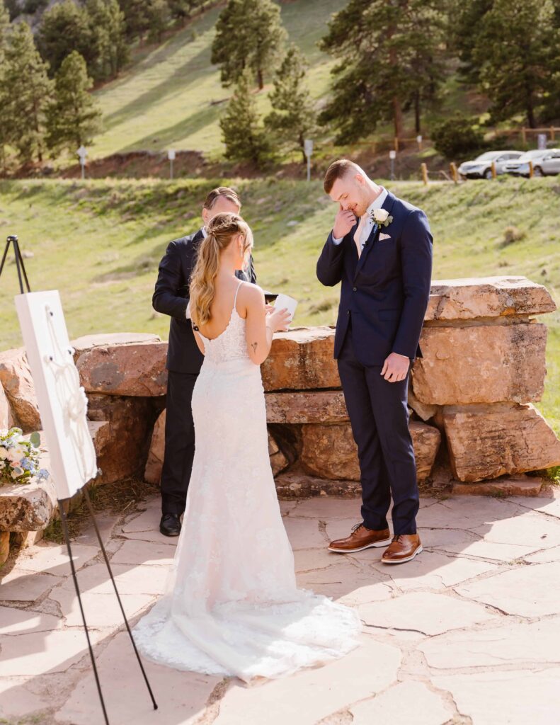 Groom wipes tears away while bride reads her vows