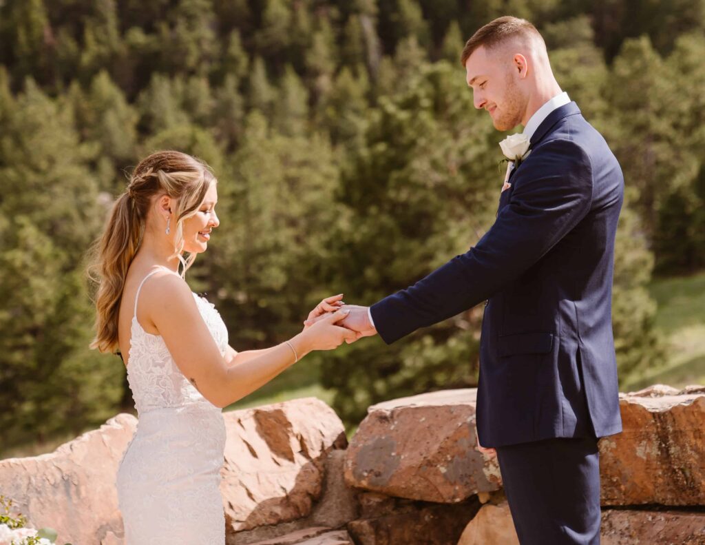 Bride places a ring on grooms finger
