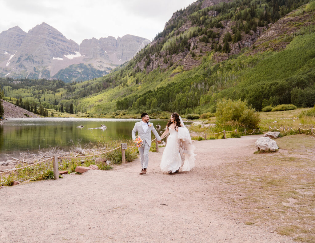 Couple runs together for their elopement at the Maroon Bells Amphitheater in Aspen, Colorado