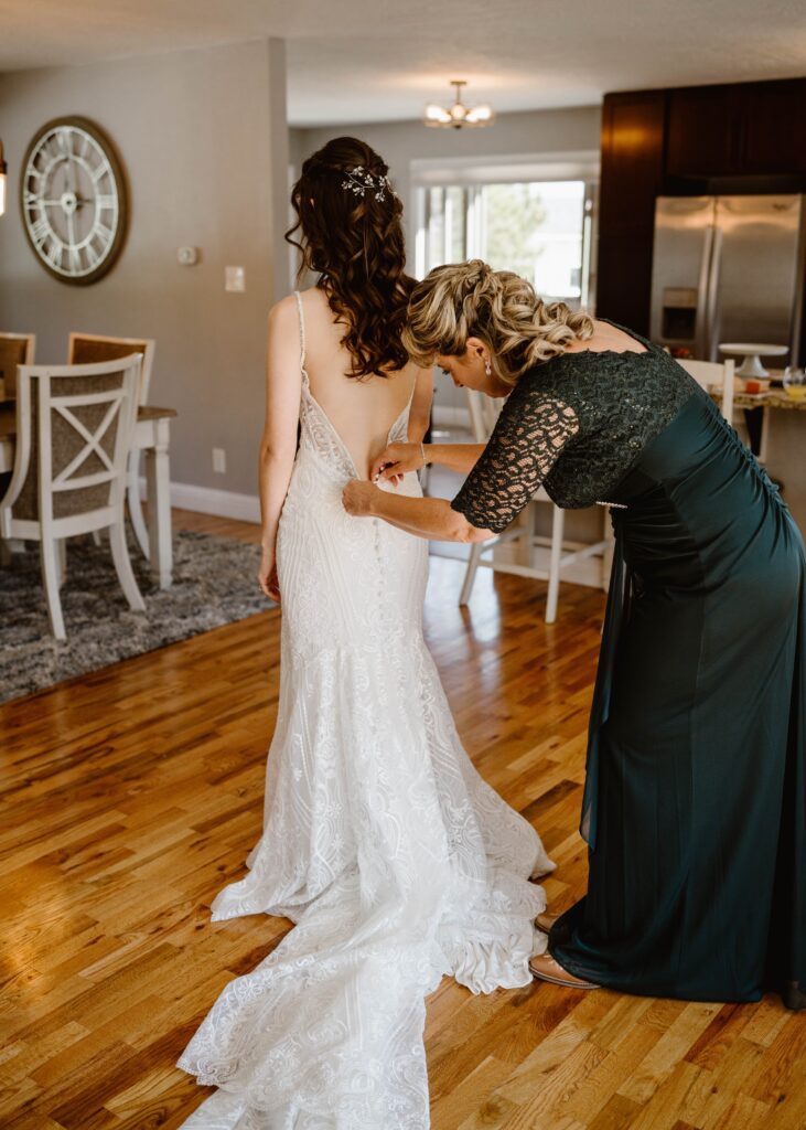 Bride's mom helps her with her wedding dress before her 3M Curve elopement