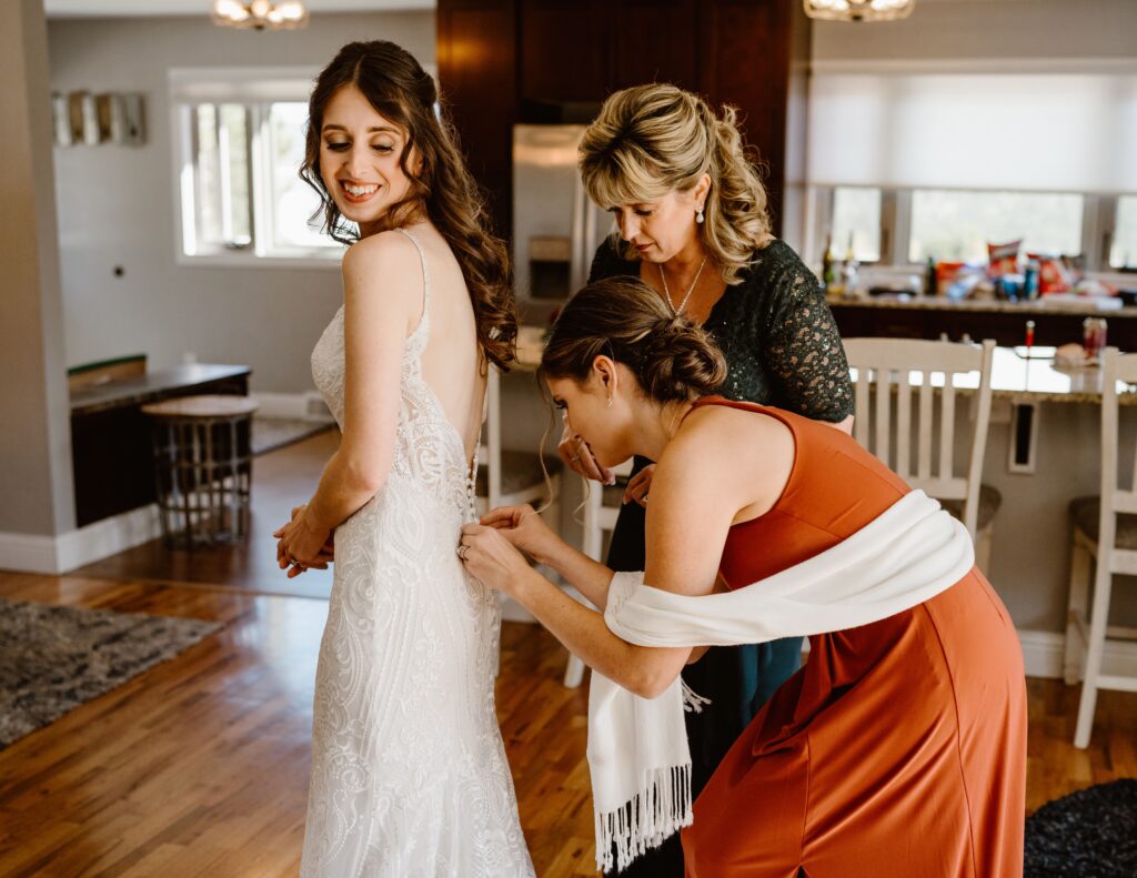 Bride's mom helps her with her wedding dress before her 3M Curve elopement