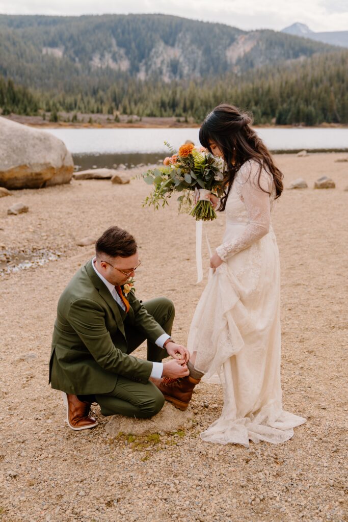 Groom helps bride put her hiking boots on