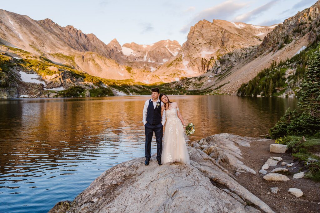 Couple stands on rocks during their Lake Isabelle elopement in Colorado at sunrise