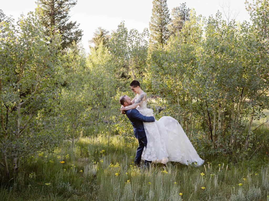 A groom lifts his bride in a forest of aspens during their Estes Park, Colorado elopement.