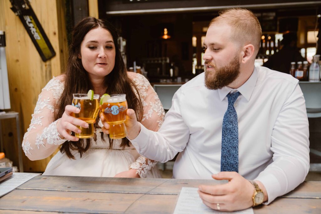 Newlyweds celebrating their Black Hawk elopement with local craft beers at a cozy bar after their mountain wedding day