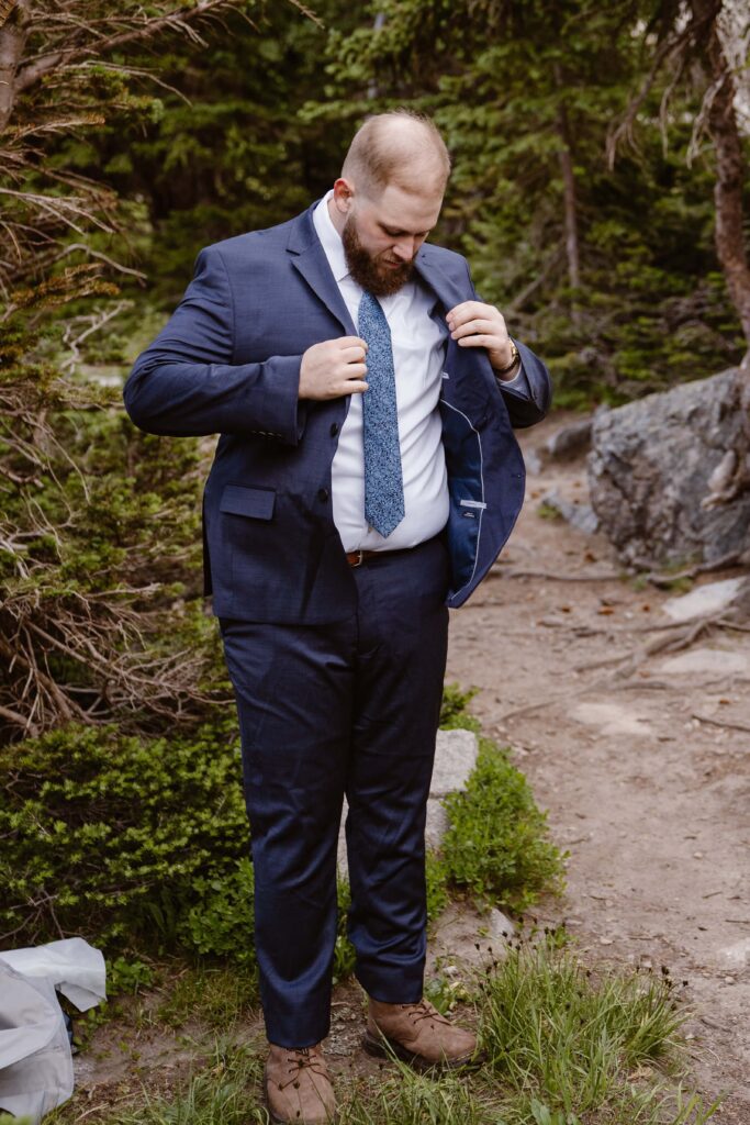 Groom adjusting his suit jacket while getting ready