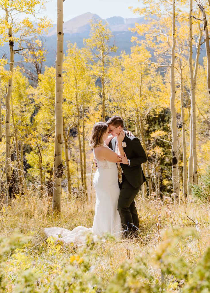 Couple share an intimate moment surrounded by golden aspen trees and mountain views during their fall elopement near Breckenridge, Colorado with Breckenridge elopement photographer and videographer Alpine Vows.