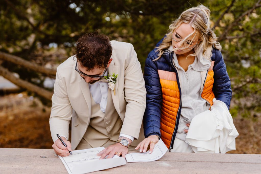 Couple signs marriage license on a picnic table
