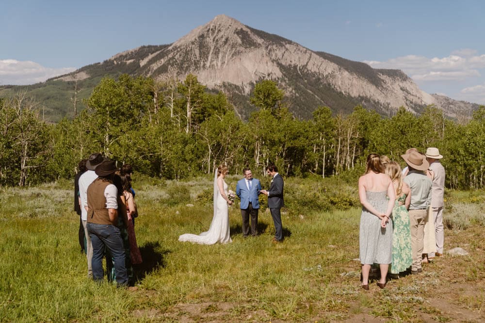 Groom reads vows to bride during their wedding at woods walk in Crested Butte, Colorado